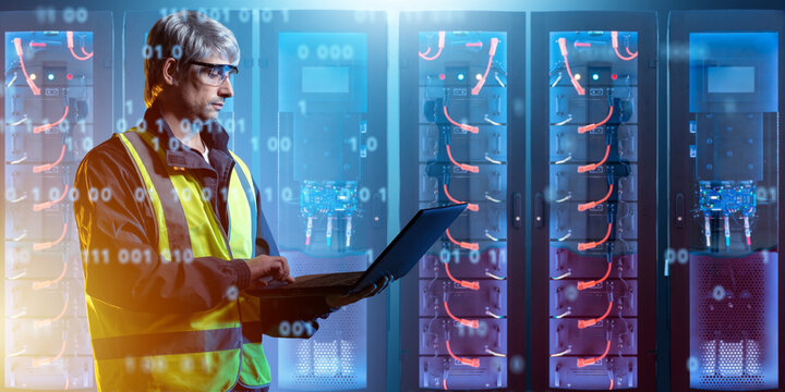 Energy storage facility. Engineer monitors battery systems and digital equipment used to store generated electricity, manage power reserves and energy distribution.