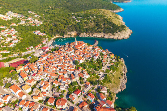 drone view of Vrbnik coastal town and natural harbor surrounded by green hills and the Adriatic Sea on Krk Island, Croatia