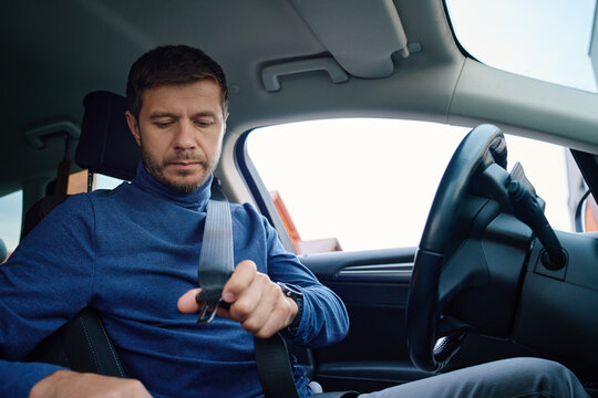 Man fastening seat belt before driving