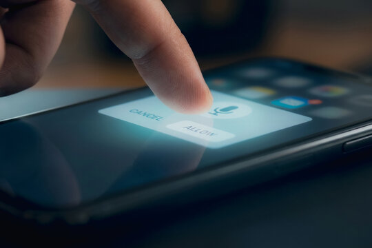 Finger touching allow button on smartphone screen