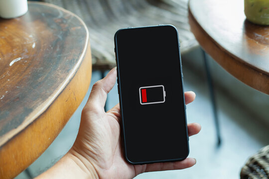 Hand Holding Smartphone Displaying Low Battery Icon