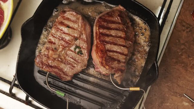 Juicy steaks searing in a hot cast iron grill pan with butter and herbs