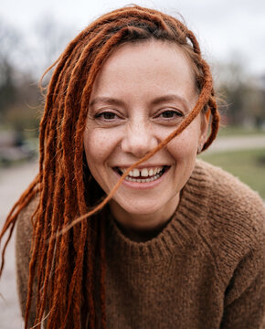 Candid close up portrait of smiling woman with red dreadlocks for lifestyle and portrait background for personal brand and social content