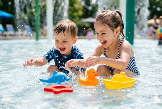 Children playing with colorful bath toys in shallow splash pool for family summer activity background