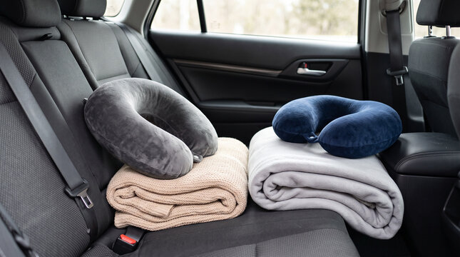 Car travel comfort accessories on backseat with neck pillows and folded blankets for road trip background and passenger rest