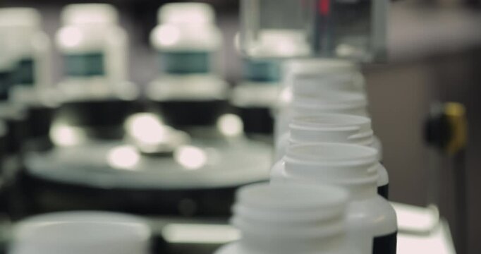 Food supplement plastic bottles motion under photoelectric sensor at factory storehouse closeup. Innovative system of vitamin manufacturing and distribution