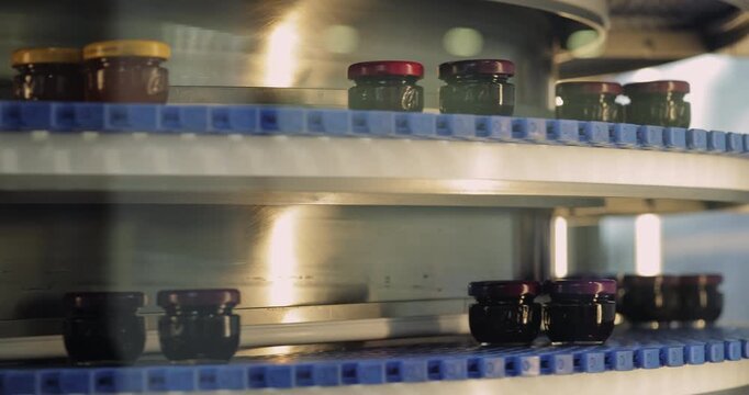 Small glass jars of organic baby food transported by modern conveyor belt. Sustainable manufacturing of healthy products for children with automated equipment