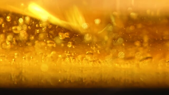 Golden oil contains suspended bubbles in a luminous macro view. Concept food advertising, cooking brands, packaging, banners and abstract design.