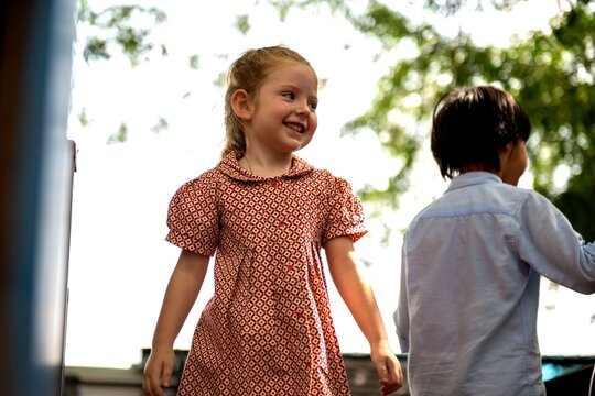 Two children playing outdoors, smiling and enjoying a sunny day.