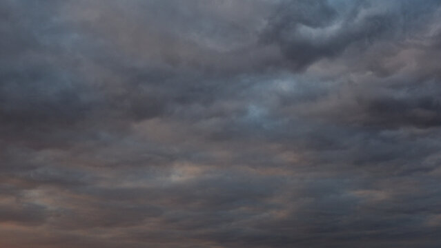 Natural backgrounds and textures. A background of a solid layer of clouds illuminated by the rays of the setting sun with small patches of blue sky. Dark background.