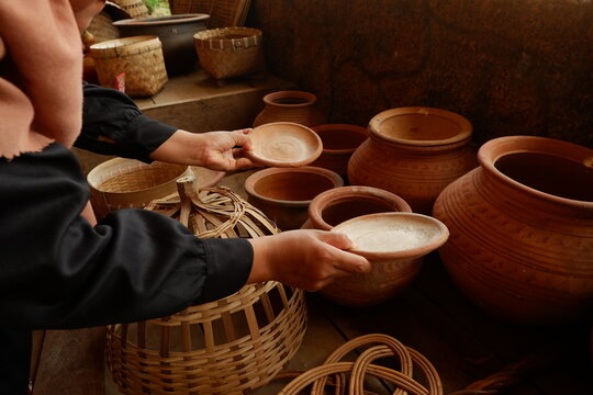Hands of buyer holding handcrafted ceramic jar at local pottery souvenir shop