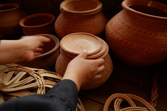Hands of buyer inspecting handcrafted ceramic jar at traditional pottery market