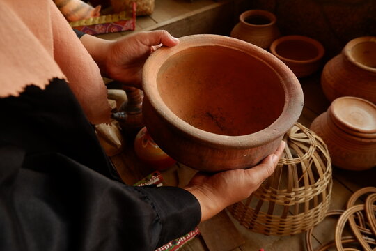 Visitor holding traditional clay pot while choosing handcrafted ceramics at market