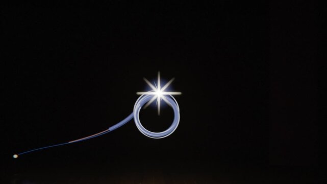 Moving light emitting blue trail in dark studio on faint grid floor, forming starburst and rings