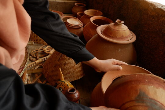 Close-up of tourist hands holding and inspecting handcrafted ceramic earthenware vessel