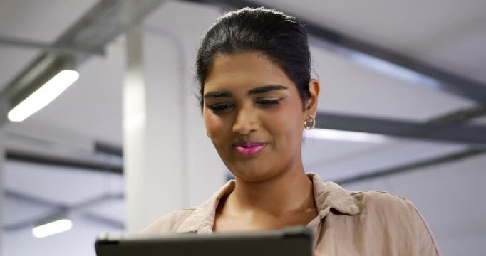 Indian woman holding tablet, reading and scrolling at modern open workspace, reviewing documents
