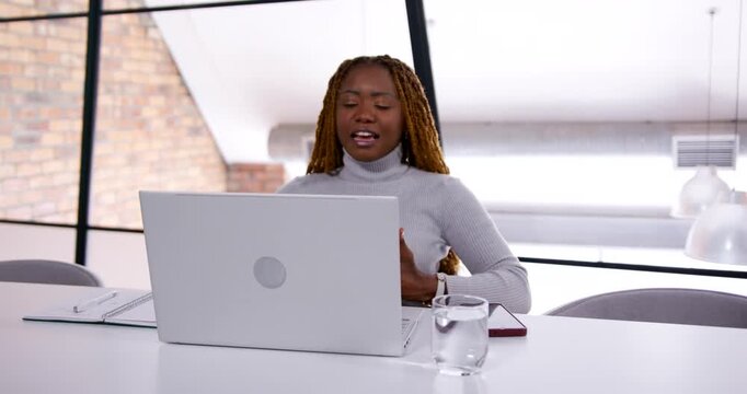 Woman smiling and introducing on incoming call in office loft, gesturing, reading laptop, frowning