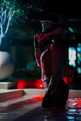 Obraz premium Motocross rider standing in a swimming pool at night while wearing a protective helmet and gear