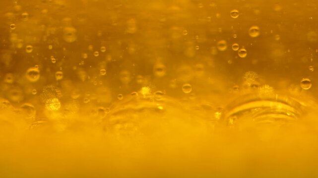 Macro view of golden oil droplets suspended in water, forming an abstract liquid texture. Concept food ingredient, science, wellness, background, packaging and advertising.