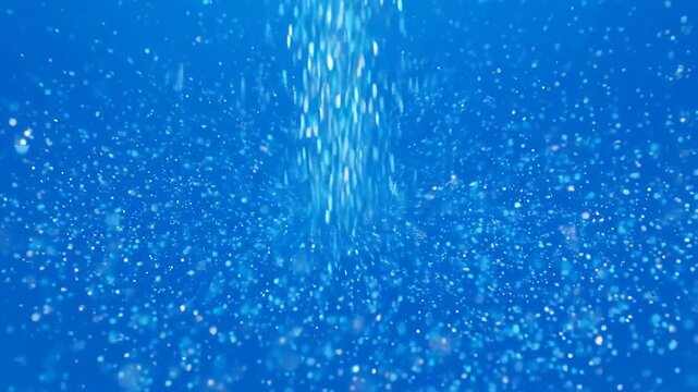 Bubbles rising in deep blue liquid with sparkling particles during underwater exploration