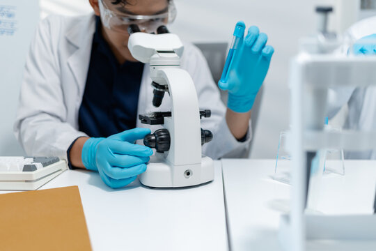 Scientists perform laboratory research using microscopes, test tubes, and modern scientific equipment to analyze samples, representing biotechnology, healthcare, diagnostics, and medical innovation.