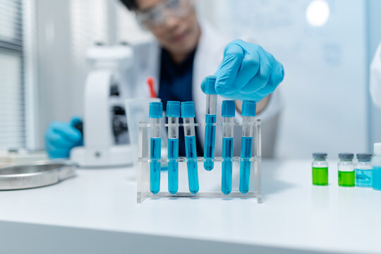Scientists analyze liquid samples using test tubes, microscopes, and laboratory equipment, representing biotechnology, medical diagnostics, research, and healthcare innovation.