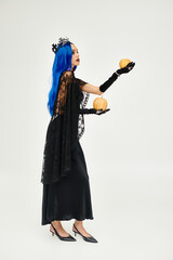 Fototapeta premium Gothic woman enchanting with blue hair and black crown in studio for Halloween
