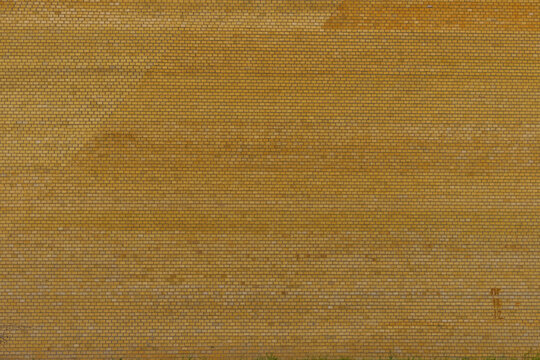 Weathered yellow brick wall with horizontal rows, subtle mortar texture, faint stains, and aged surface detail