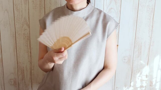 扇子で風を送り暑さに耐える日本人女性