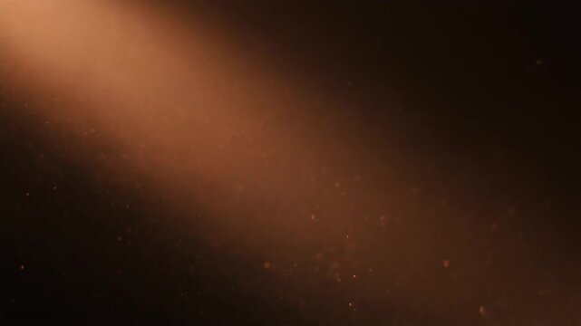 Warm copper dust drifts and swirls through diagonal backlight, particles catching soft glow against deep black with dreamy industrial atmosphere, cinematic depth, and gentle motion.