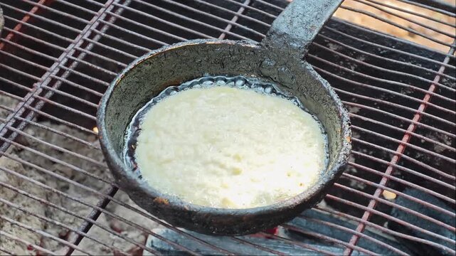 Making potato pancakes called draniki in a frying pan over open flames
