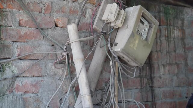 Old electrical meter with exposed wires on weathered brick wall for urban farming setup