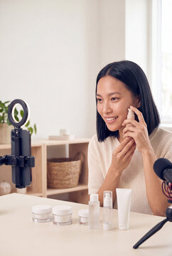 Woman demonstrating skincare products on camera for beauty vlog tutorial and product review banner background for social media
