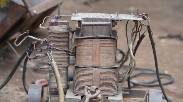 Old rusty electrical transformer coil with exposed copper wiring for industrial repair.