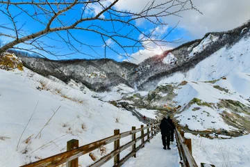 Tourist standing on wooden boardwalk looking at dramatic active volcanic crater in Jigokudani winter season © I Viewfinder