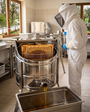 Worker extracting honey using a stainless steel extractor.