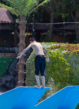 Young man prepares to jump off blue slide
