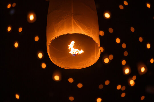 Sky lantern floating in the dark night sky, Tourist floating sky lanterns, Sky lanterns floating on night of Yi Peng, Loy Krathong Festival or Yi Peng Festival in Chiang Mai Thailand.