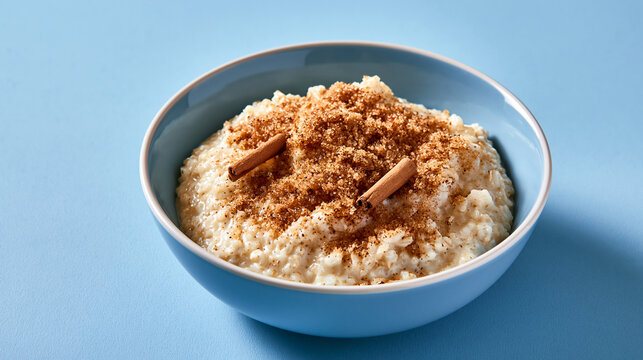 A blue bowl of creamy rice pudding topped with cinnamon and brown sugar. Perfect for a cozy comfort food dessert menu.