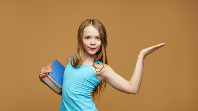 A happy schoolgirl with a books stands on an isolated background. Back to school and joy of learning concept.