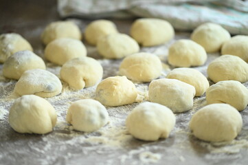 Fototapeta premium Preparation of homemade yeast dumplings on a rustic wooden table, filled yeast dumplings ready for cooking, traditional Czech cuisine, homemade cooking, dough preparation
