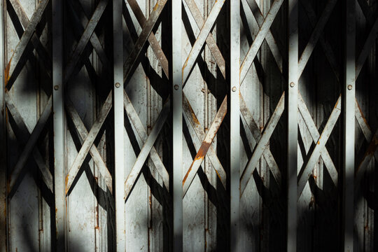Old Metal Folding Gate with Repeating Diamond Pattern and Shadows