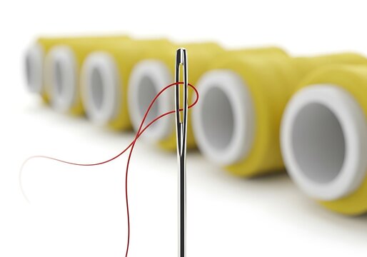 Close-up of a Silver Sewing Needle with Red Thread and Blurred Yellow Spools