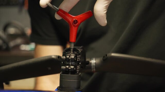 Bike mechanic loosens the handlebar stem bolts with a tool during bicycle repair. Professional bike maintenance and workshop service concept