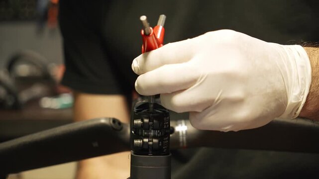 Bike mechanic loosens the handlebar stem bolts with a tool during bicycle repair. Professional bike maintenance and workshop service concept