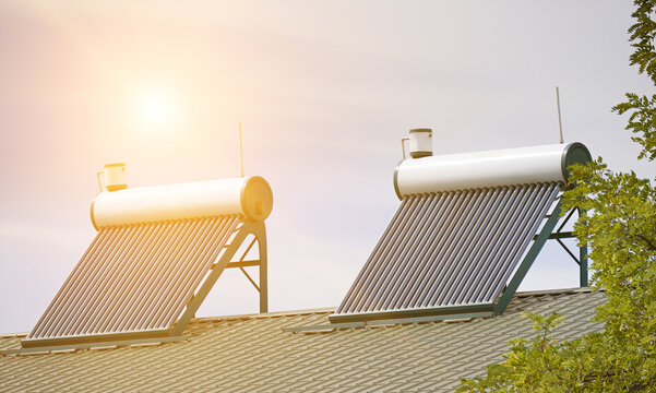 Solar Water Heater Panels with Evacuated Vacuum Tubes Installed on the Roof of a Modern House against Sunrise Sky. Green Ecofriendly Energy System for Residential Infrastructure.