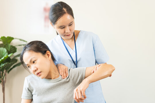 Asian young woman physical therapist guiding a patient through shoulder and neck stretching exercises for office syndrome relief, rehabilitation and occupational therapy concept.