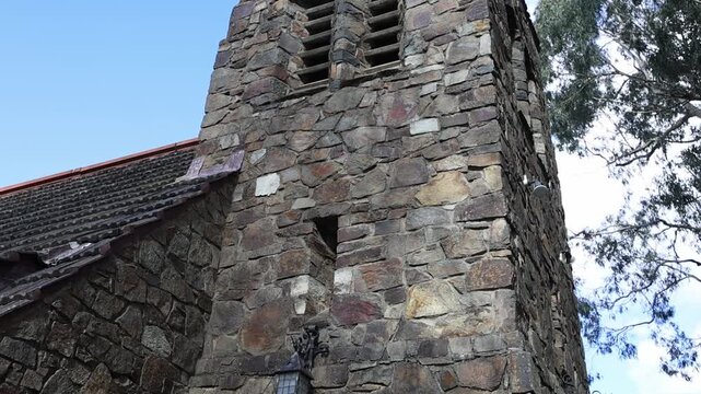 Medieval stone church tower pan down to red door