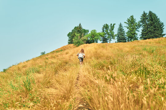 Boy running up a dry grassy hillside on a summer day