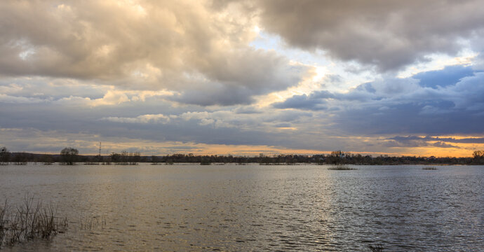 Dramatic clouds above reflective lake at golden hour